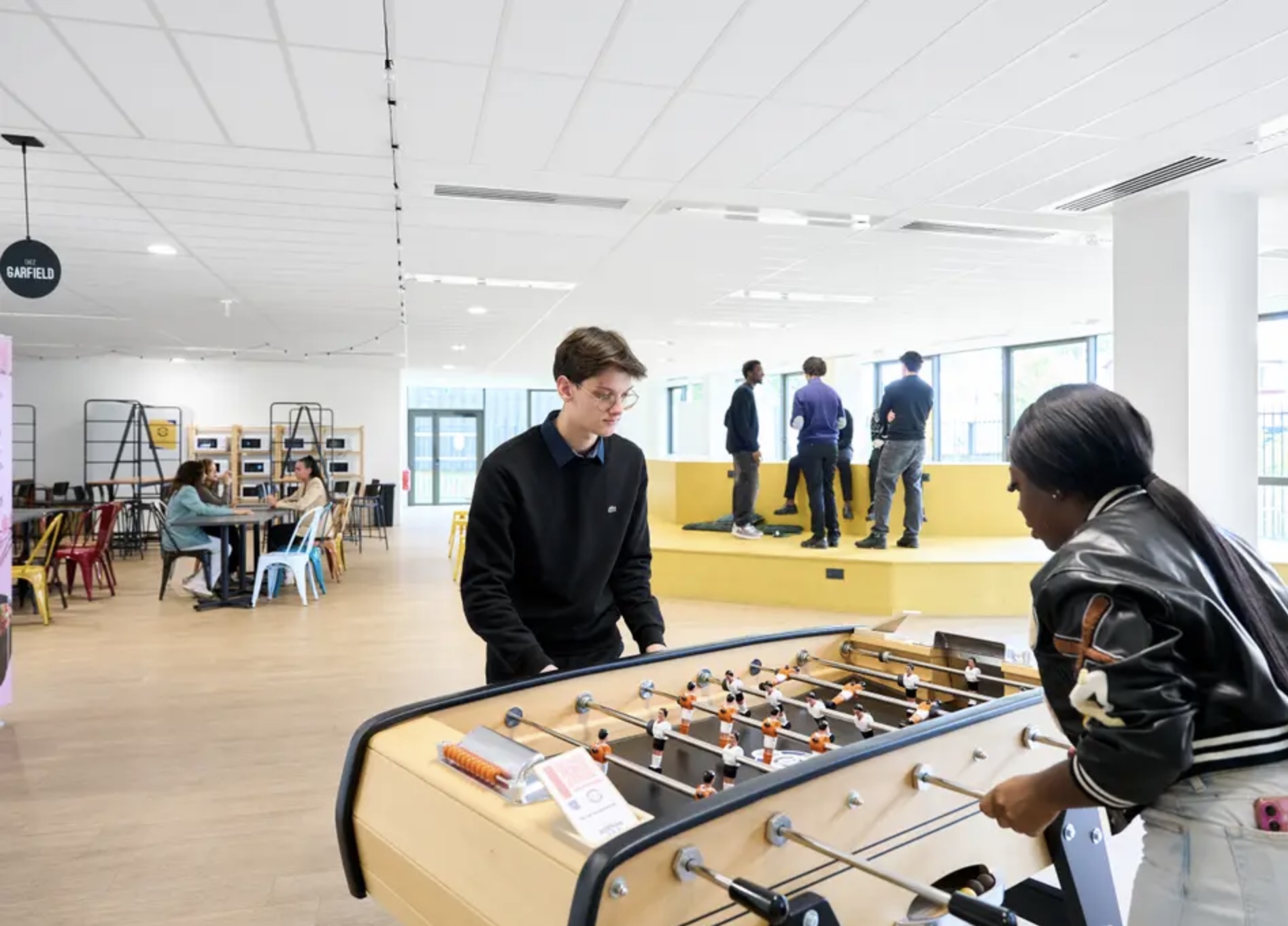 Étudiants jouant au baby-foot dans l'espace cafétéria du campus