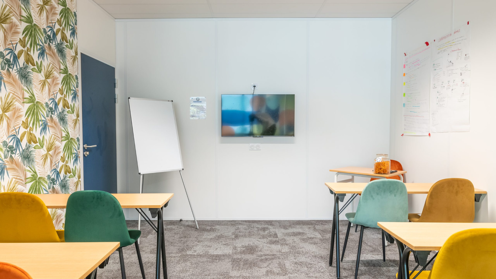 Salle de formation avec paperboard, écran mural et chaises colorées