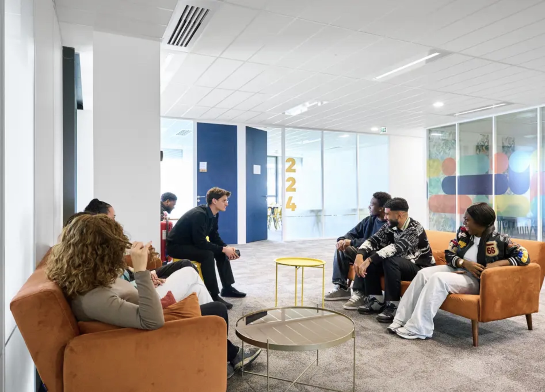 Groupe d'étudiants discutant dans un salon avec fauteuils orange