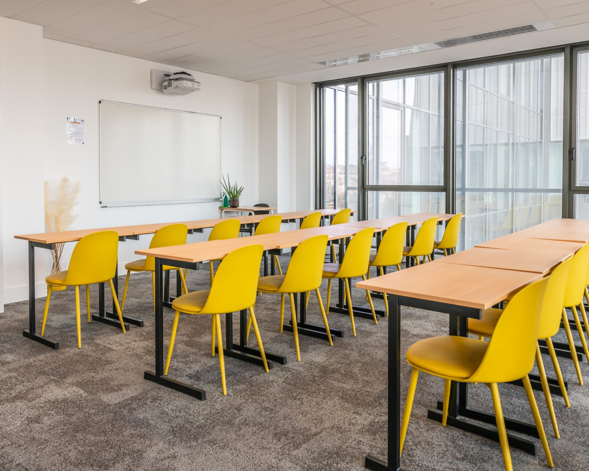 Salle de cours lumineuse avec chaises jaunes et grandes baies vitrées