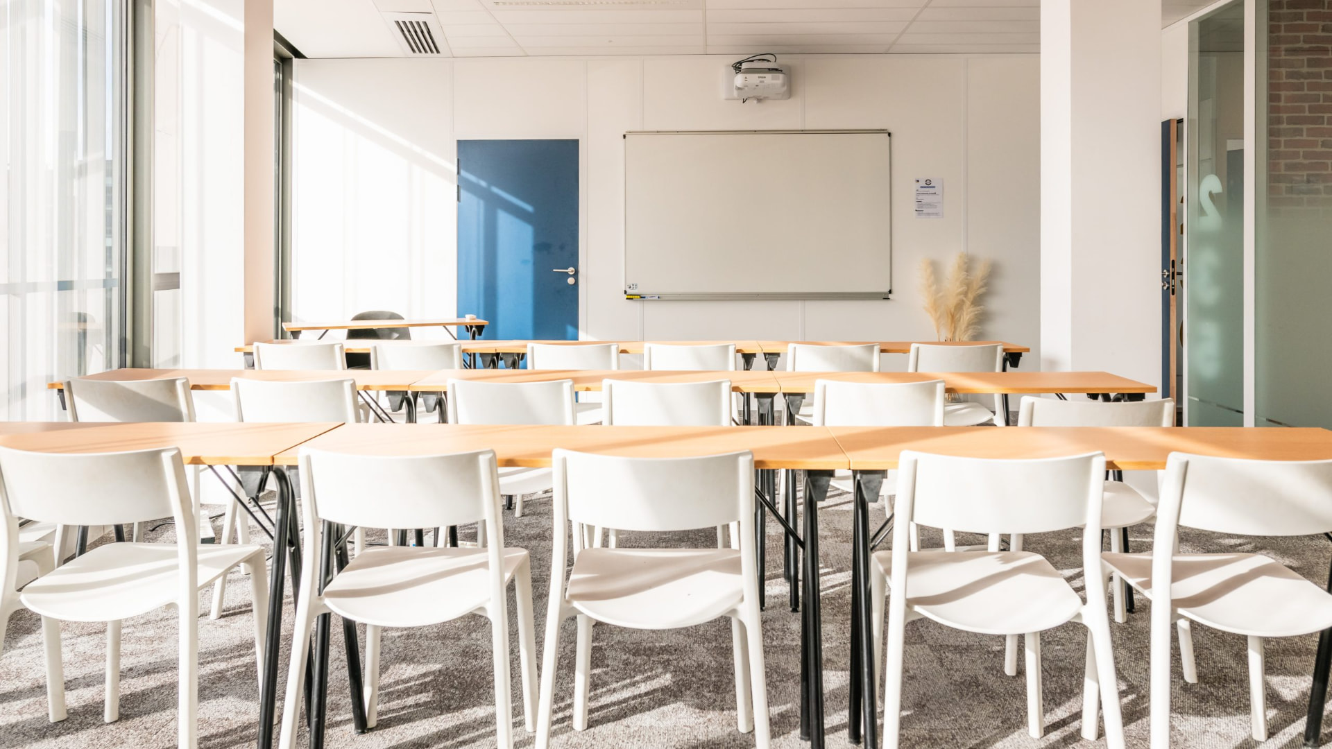 Salle de classe claire avec chaises blanches et tableau blanc